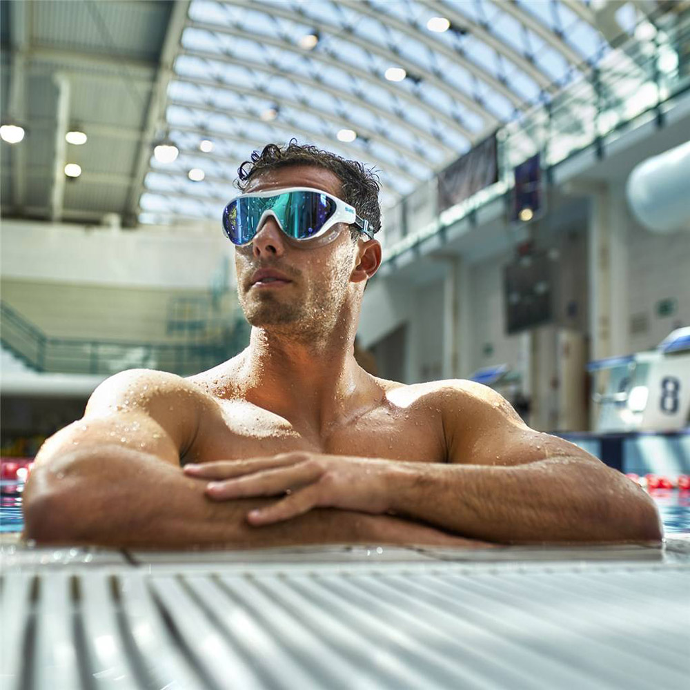 Hombre con gafas de natación buceando en piscina